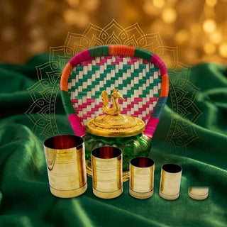 Palm leaf muram (solavu, winnowing tray), green and gold coins pot and brass azhakku (padi) measuring cups on green velvet