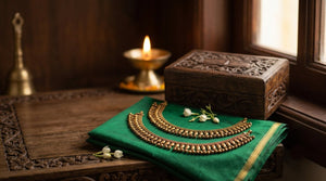 Pair of Impon kolusu (five-metal anklets) with mango charms and small bells on green silk saree fabric