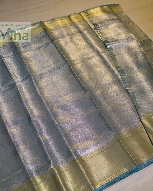 Premium Katan Silk Saree With Blouse, folded blue fabric featuring a leaf pattern and gold-toned borders