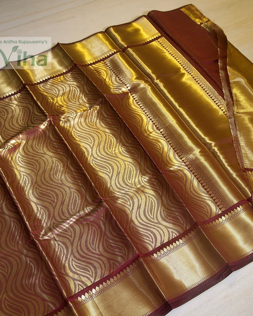 Premium Katan Silk Saree With Blouse, a shiny maroon fabric with wavy gold-toned patterns and wide glossy borders