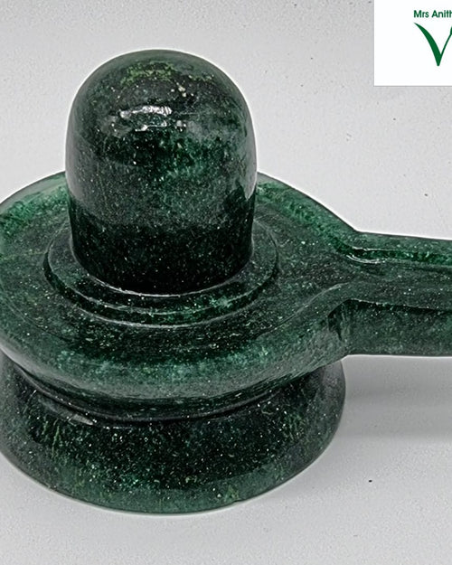 Green Jade Shivling, a dark green mottled stone sculpture featuring a rounded vertical pillar rising from a circular tiered base with a side spout