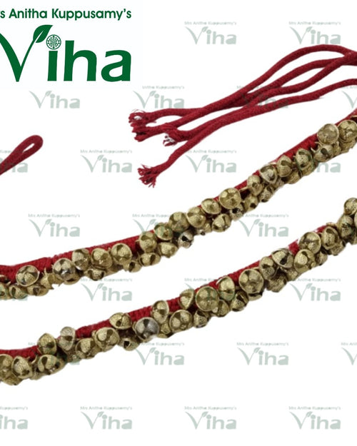 Dancing Ghungroo, two parallel red fabric cords adorned with numerous small, textured, gold-toned metallic bells feature tied ends