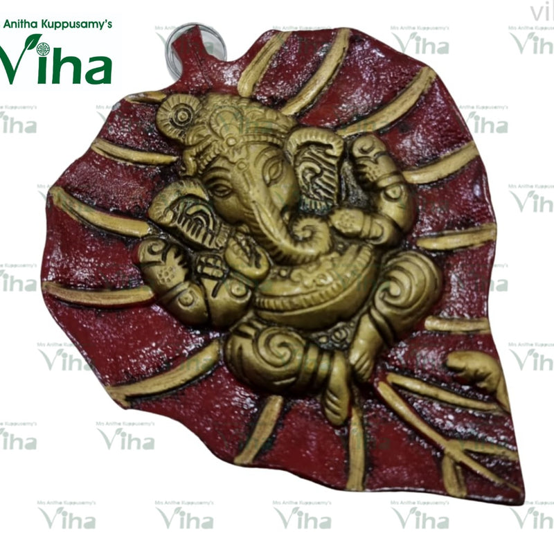 Leaf Ganesha Wall Hanger, a gold-toned relief figure on a red-and-gold leaf-shaped plaque with textured surface finish