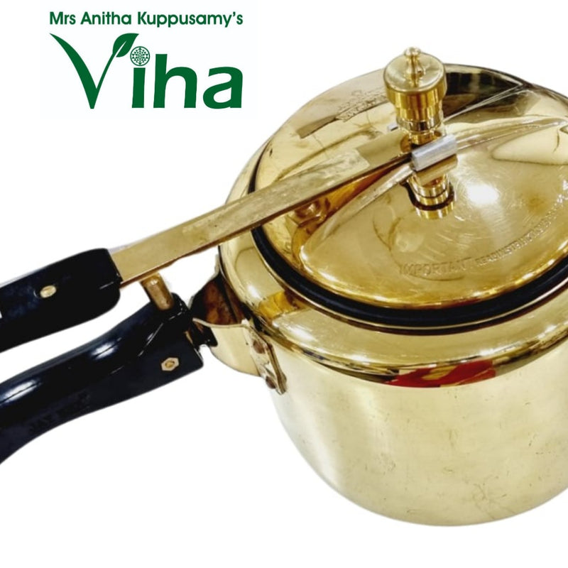 Brass-toned pressure cooker with black handles and a gold pressure valve