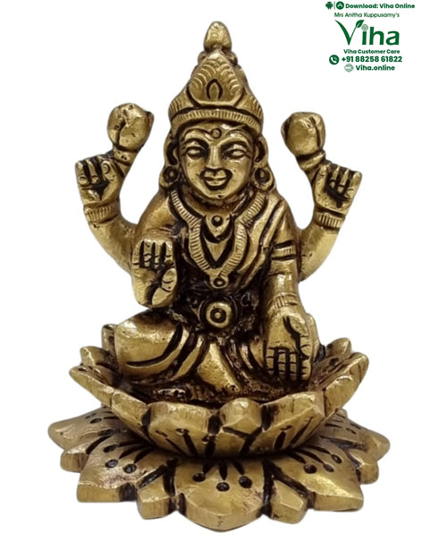 Mahalakshmi in brass, four-armed figure seated on an open lotus base with spread petals