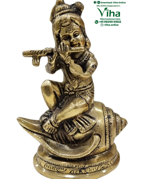 Sankh Krishna in brass, figure playing a flute seated on a conch-shaped base over a round pedestal