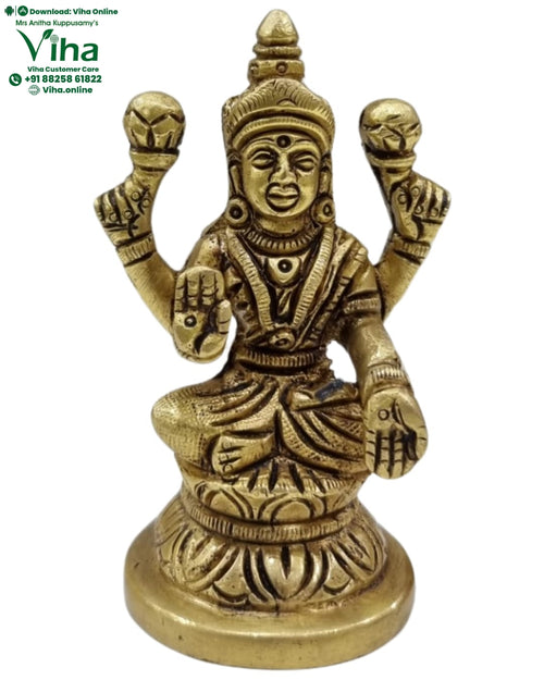 Mahalakshmi in brass, four-armed figure seated on a round stacked pedestal