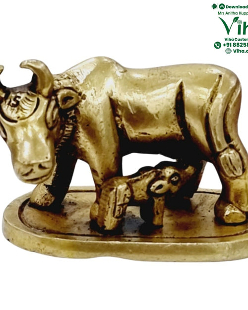 Cow and calf in brass, a horned cow with the head lowered to a calf standing beneath, on an oval base