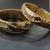 Impon Toe Ring, two gold-toned metal rings featuring dual rows of small raised dots along their curved bands against a dark surface