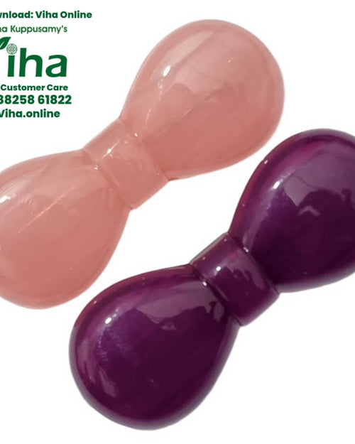 Saree Pin, two glossy, rounded, bow-shaped objects in pale pink and dark purple lie diagonally