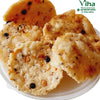 Tasty Milagu Thattai, a pile of golden-brown, round fried snacks with textured, uneven surfaces and dark peppercorns inside, in a clear plastic bowl