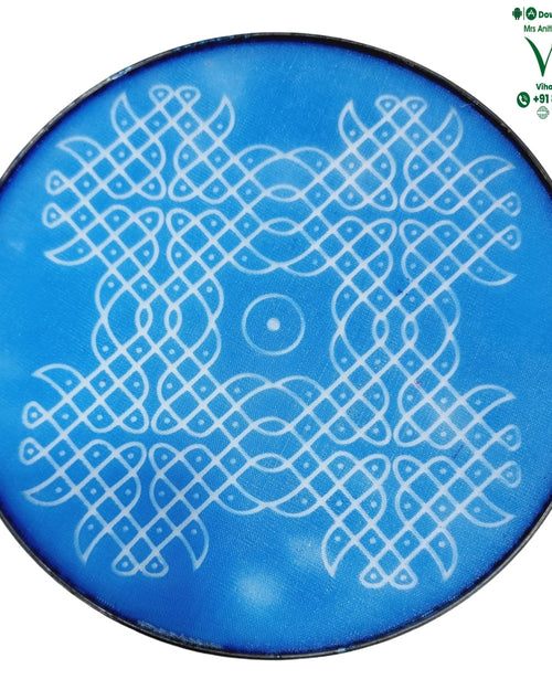 Rangoli Stencil Plate, a round blue plaque featuring a white interwoven geometric pattern with a central concentric circle and a thin dark border