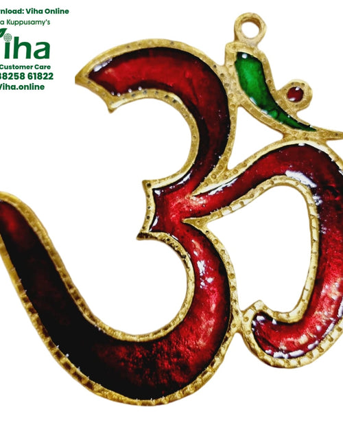 Om Wall Hanging, a gold-toned metallic Om symbol featuring glossy red enamel fills, one green area, and a red stone detail with a loop at the top