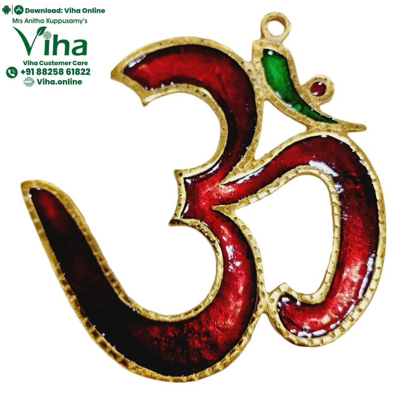 Om Wall Hanging, a gold-toned metallic Om symbol featuring glossy red enamel fills, one green area, and a red stone detail with a loop at the top