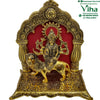 Durga in white metal, multi-armed figure on a lion within an ornate arch with a red backing panel