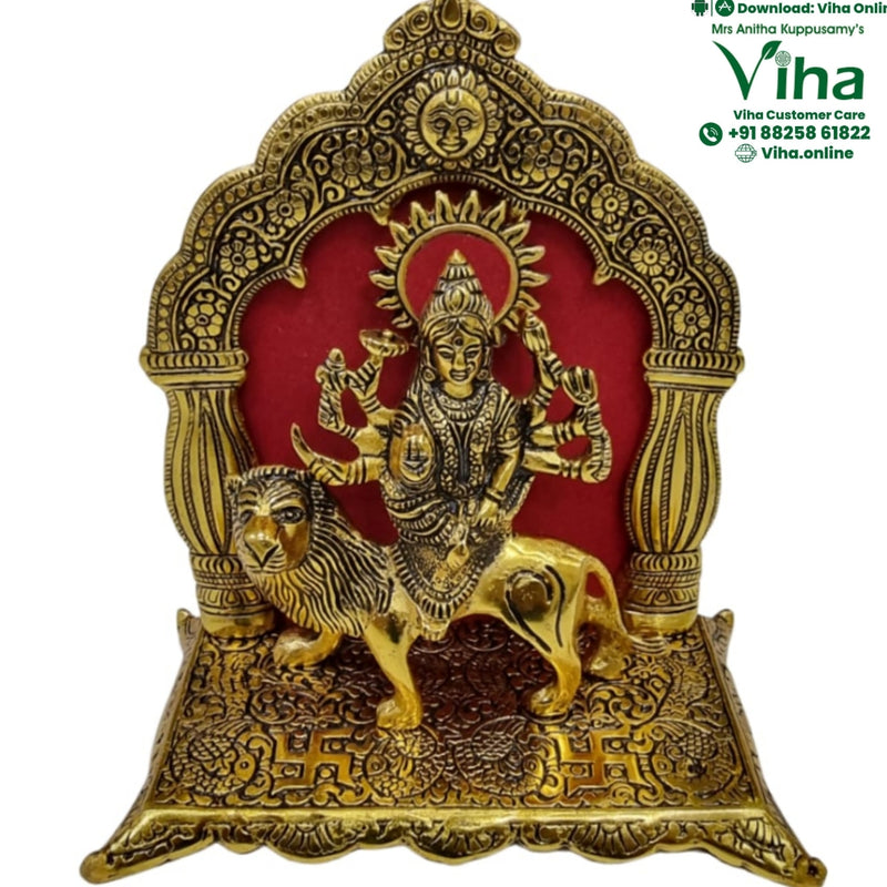 Durga in white metal, multi-armed figure on a lion within an ornate arch with a red backing panel