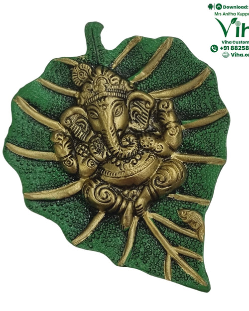 Green Leaf Ganesha Wall Hanger, a green-textured leaf sculpture featuring an elephant-headed figure in gold-toned finish with multiple radiating stems