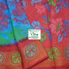 Soft Cotton Saree With Blouse, a red fabric features blue and green floral patterns alongside a blue tie-dye section and a border with seven circular motifs