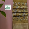 Cotton Silk Saree with Blouse, a folded olive-green fabric features a metallic-toned border and a white leaf pattern across its surface