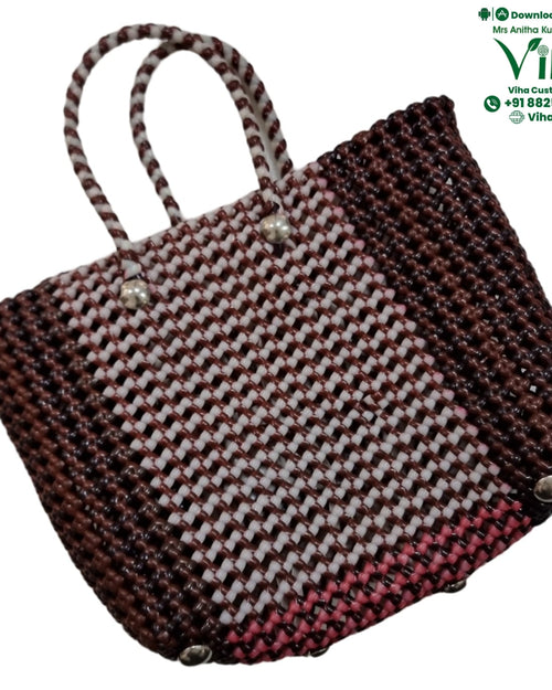 Wire Koodai, a woven tote bag features a brown, white, and pink checkered pattern, two arched handles, and three silver-toned feet on the base