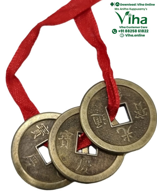 Fengsui Coin, three brass-toned round metal coins with square center holes and embossed Chinese characters threaded on a red ribbon