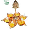 Arumuga 6 face Vel Lamp, a metallic gold-toned fixture holds six small, round, lit oil lamps surrounding a central upright stem topped with a pointed emblem