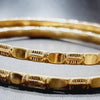 Impon Bangle, two round gold-toned bangles with a glossy finish, textured grooves and smooth rectangular links