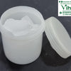Pachai Karpooram, an open, round, translucent white plastic jar containing four white crystalline chunks, beside its detached, ridged screw-on lid