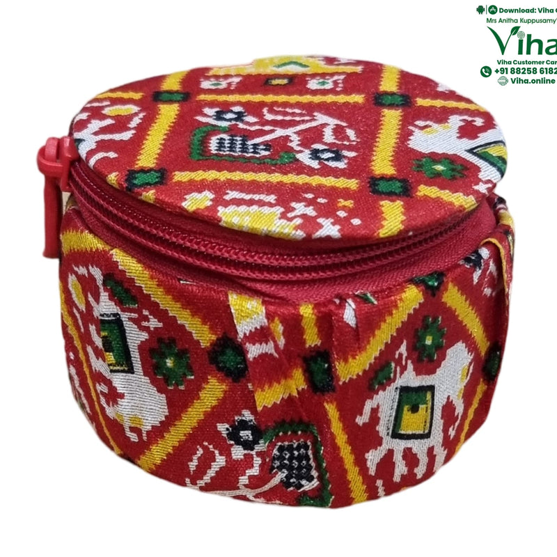 Storage Box, a small, round red zippered pouch features a patterned fabric cover in red, yellow, white, and green with geometric and animal motifs