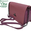Sling Hand Bag, a dark pink handbag with textured surface, curved flap, metallic emblem, two dark-toned chains, and an adjustable strap