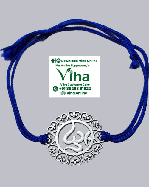 White Metal Rakhi, a grey-toned circular metal pendant with an ornate heart-cutout border and a central symbol, threaded onto a dark blue string
