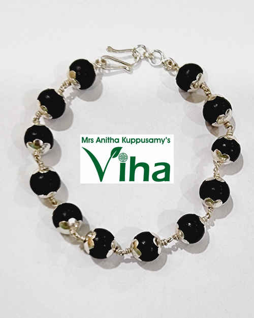 Karungali Bracelet Silver with Cappings, a bracelet with twelve black spheres and silver-toned metal caps linked by twisted wire on a white surface