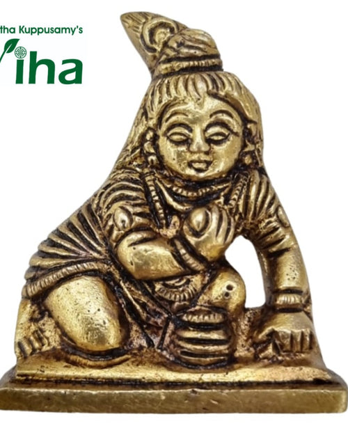Krishna in brass, child figure leaning forward on one arm against a flame-shaped backslab