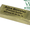 Aura Booster, a gold-toned rectangular block with black text printed on its top surface