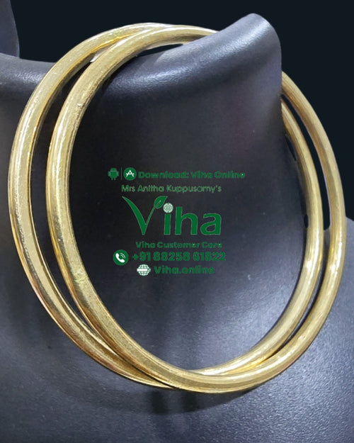 Impon Bangle, two round, shiny, gold-toned plain metal bangles displayed on a dark grey stand