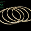 Impon Bangle, four gold-toned metal bangles with faceted surfaces overlapping diagonally on a black background