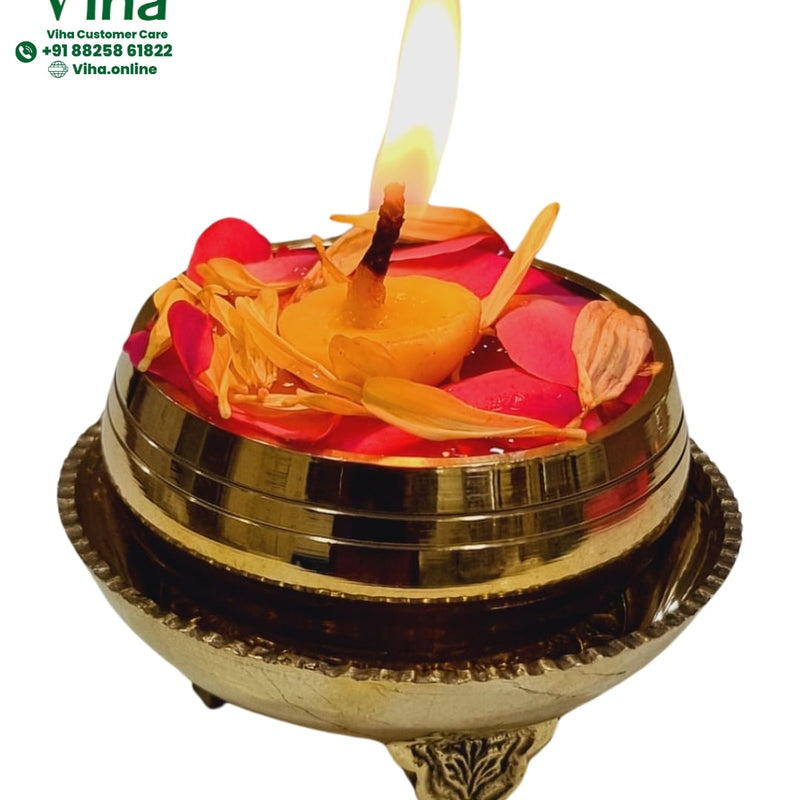 Jaladeepam mini urli in brass on three legs, water with floating flower petals and a lit wick