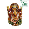 Decorated wooden Ganesha, hand-painted face with large ears and a downward curved trunk against a painted arch