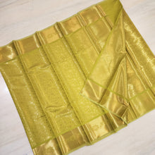 Designer Silk Saree With Blouse, a folded gold-toned fabric with a glossy finish, featuring intricate woven floral and geometric patterns