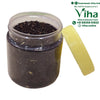 Cardamom Tea, an open, transparent plastic jar filled with dark brown loose herbs stands beside its matching pale yellow-green screw lid