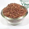 Mappillai Samba Rice - Organic, a glass bowl filled with reddish-brown rice grains on a white surface