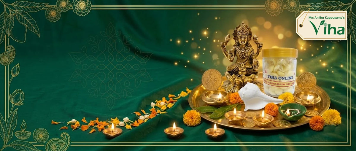 Viha Dhanteras and Diwali pooja items on a brass plate: brass Mahalakshmi statue, lit brass diyas, Lakshmi Kuber vilakku, green Kuberar agal vilakku, valampuri sangu (conch) and Viha ghee deepam (ghee lamp wicks) in a gold-framed banner