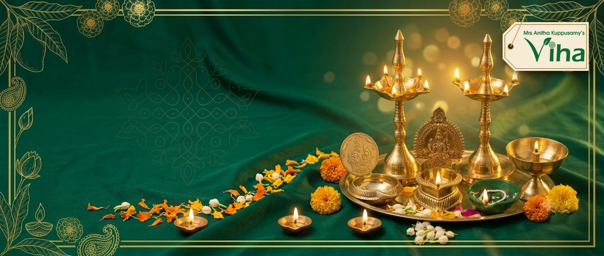 Viha brass lamps lit on a brass plate: two 5-face kuthu vilakku (standing oil lamps), Lakshmi Kuber vilakku, Kamakshi Amman vilakku, Kuberar green agal vilakku (clay diya) and athma vilakku, with small agal vilakku (oil lamps), marigold petals and a gold kolam (rangoli) pattern in a gold-framed banner