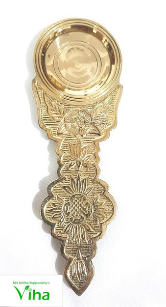 Dhoobakkarandi, a shiny gold-toned metal object with a round bowl top and a decorated handle featuring embossed floral patterns against a textured background