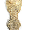 Dhoobakkarandi, a shiny gold-toned metal object with a round bowl top and a decorated handle featuring embossed floral patterns against a textured background