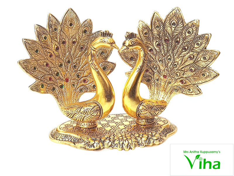 Double Peacock (Showpiece), two gold-toned peacocks with spread, textured tail feathers set with red and green stones, facing each other on an oval base