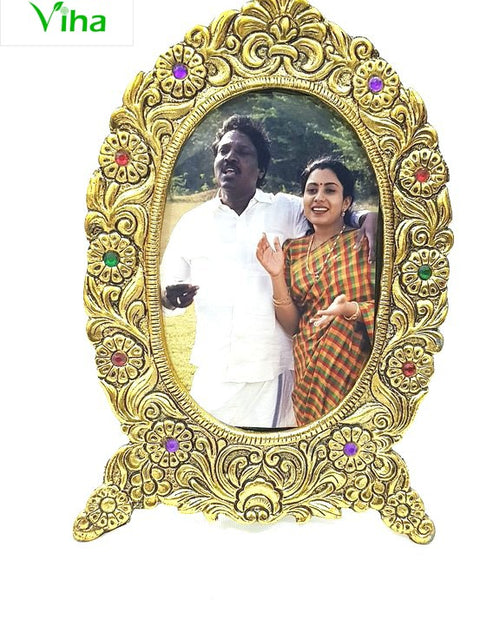 Jaipur Photo Frame Oval Shape, an ornate gold-toned oval standing frame holding a photo of a man and a woman, with coloured stone flowers