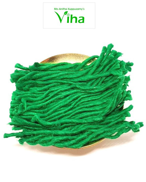 A coiled bundle of bright green cotton lamp wick in a gold-toned dish