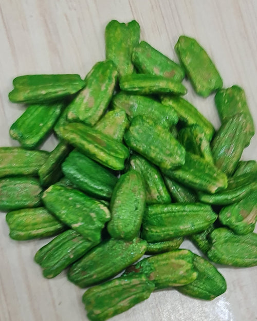 Sombu Gourd Seeds, pale green oblong seeds piled together on a wooden surface