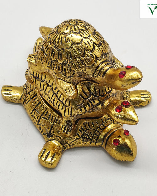 Triple Tortoise, three stacked gold-tone tortoises with engraved shell patterns and red gem eyes